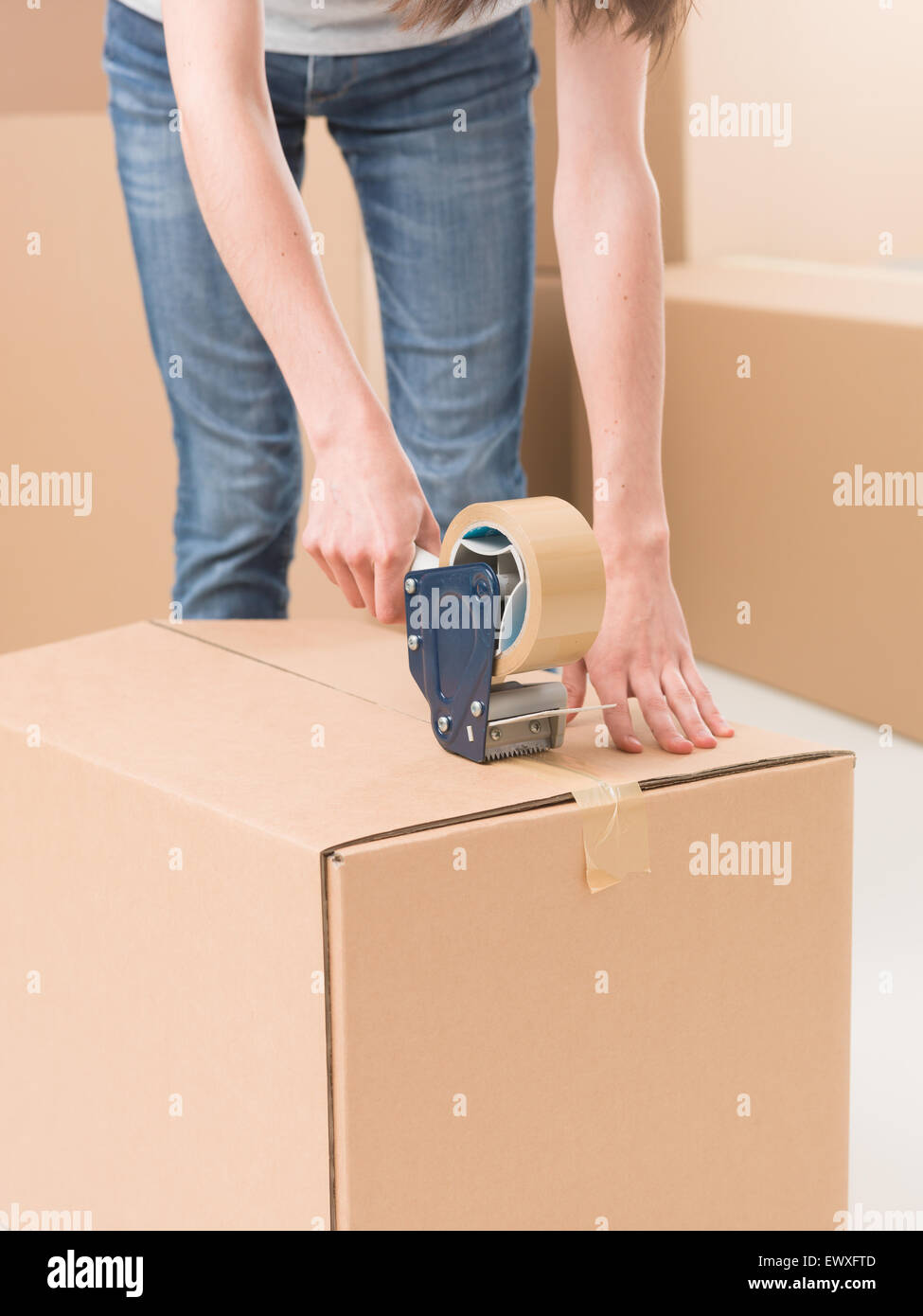 closeup of female sealing cardboard box with adhesive tape Stock Photo