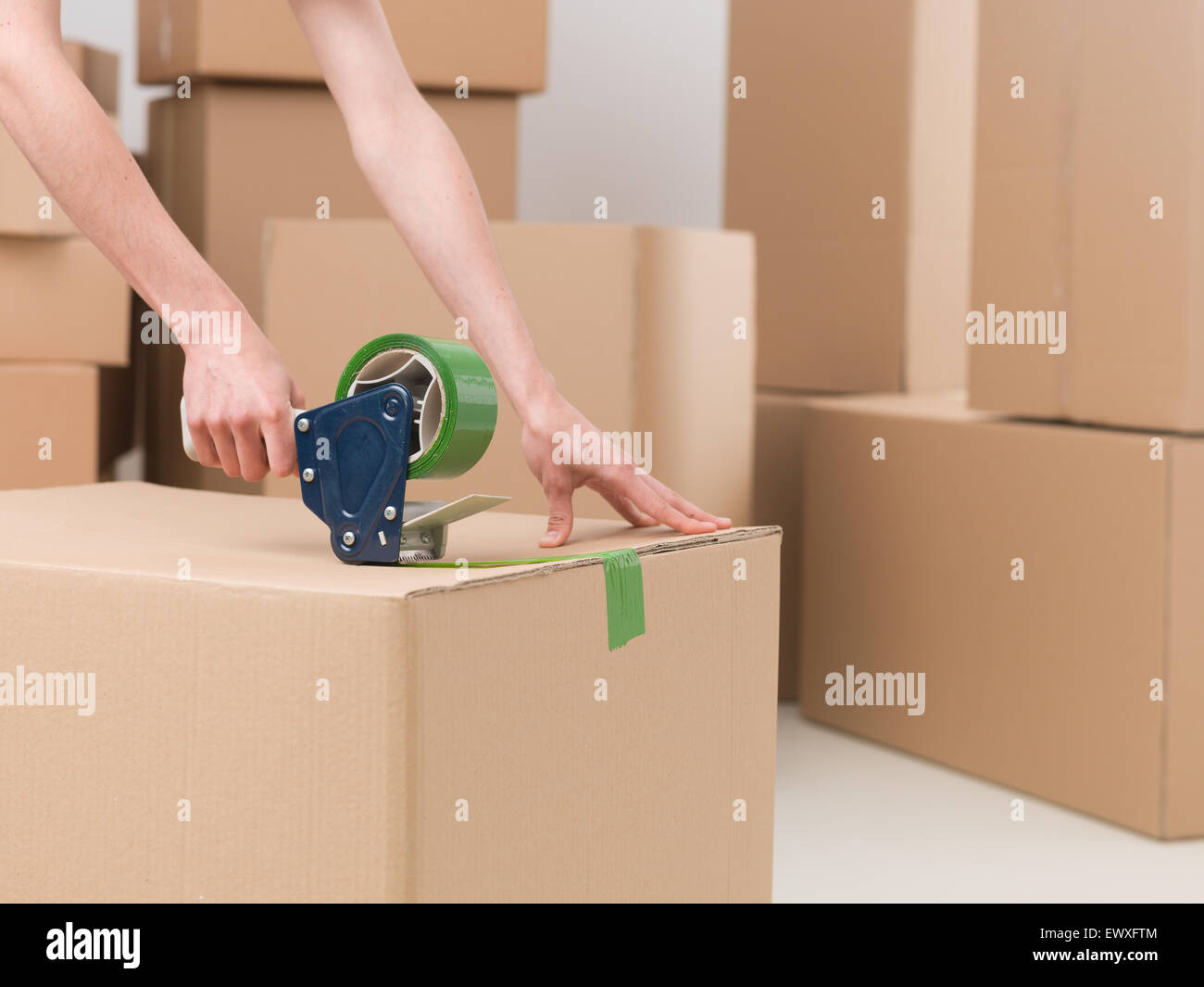 closeup of female sealing cardboard box with green duct tape Stock