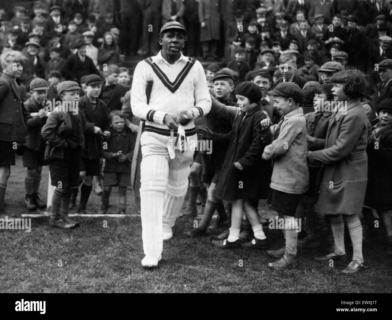 West Indies cricketer Learie Constantine walks out on to the field past excited children. Circa 1932. Stock Photo