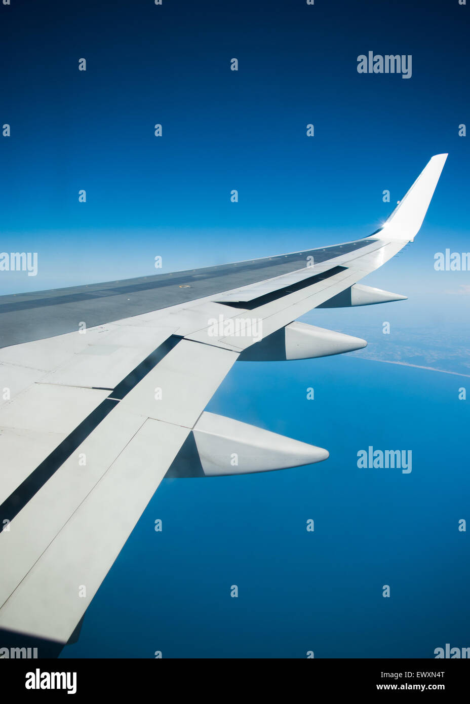 Airplane wing against a blue sky Stock Photo - Alamy