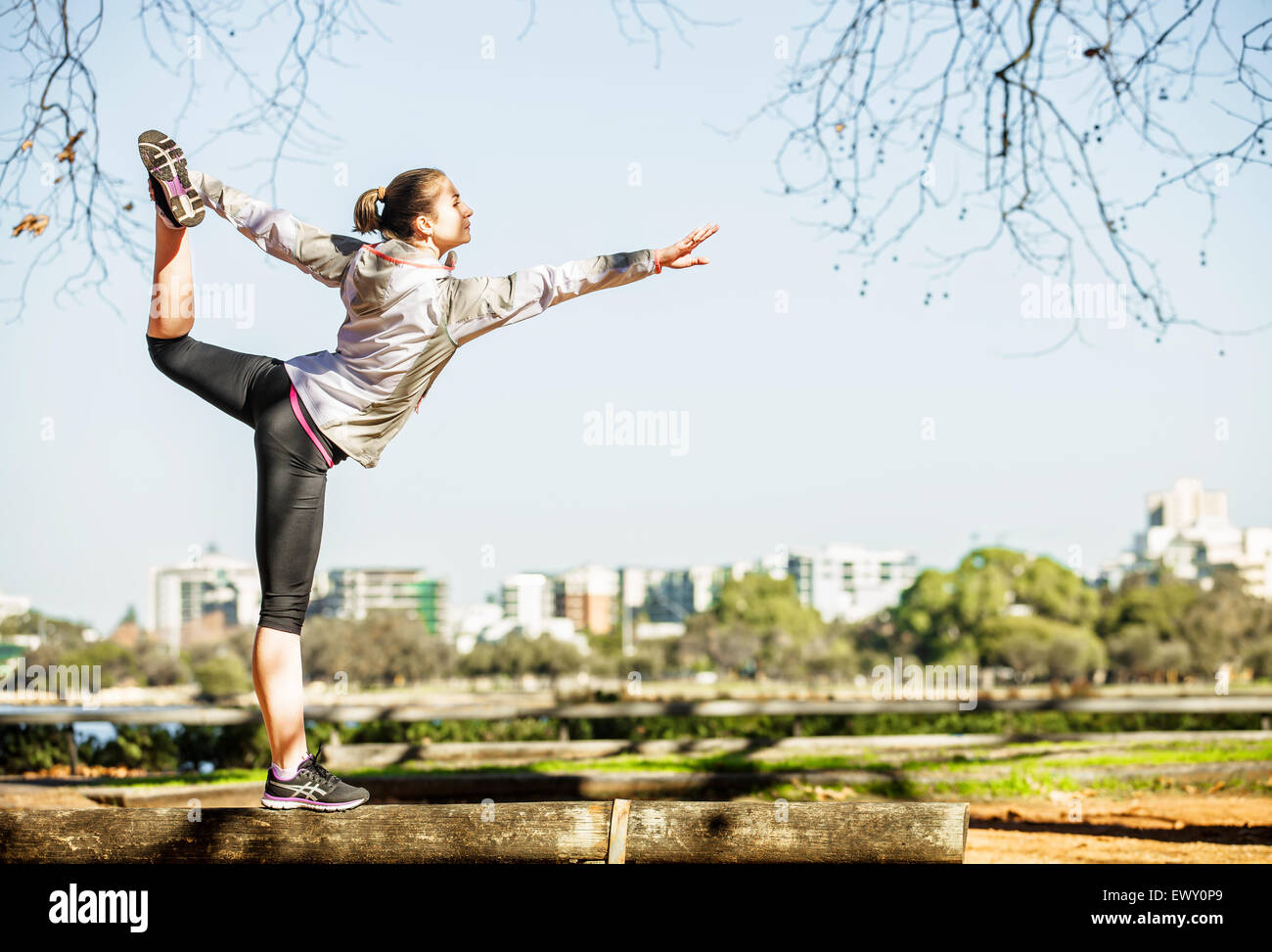 Young Woman Stretching Out On Bench Before Jogging In Autumn