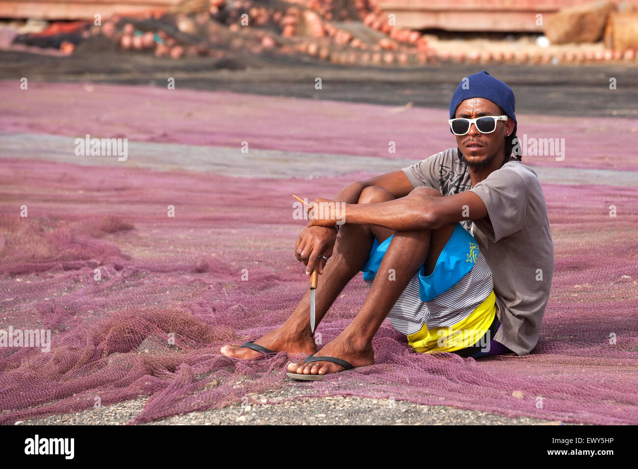 Creole fisherman mending fishing nets in the harbour of fishing village ...