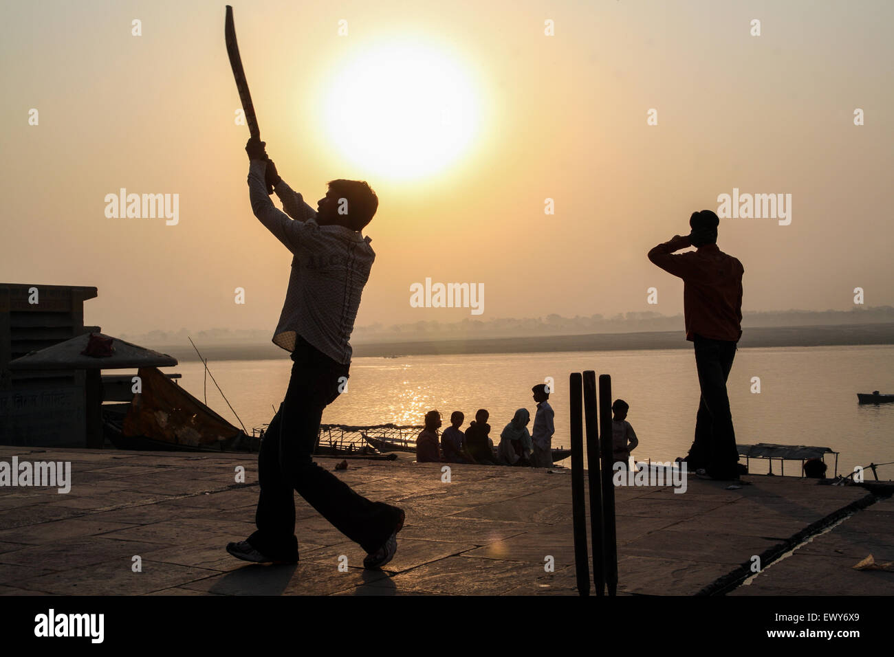 Local boys, on bathing ghat, playing popular national sport of cricket at sunrise. A good hit and the ball goes into the River Ganges. The culture of Varanasi is closely associated with the River Ganges and the river's religious importance.It is 'the religious capital of India'and an important pilgrimage destination.Varanasi, also known as Benares, an ancient city, one of the world's oldest continually inhabited cities, situated on the left/west bank of the sacred Ganges River. Regarded as holy by Hindus, Buddhists, and Jains. Uttar Pradesh State, India, Asia. Stock Photo