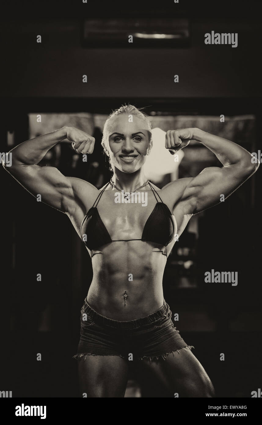 Serious Woman Bodybuilder Standing In The Gym And Flexing Muscles Stock Photo