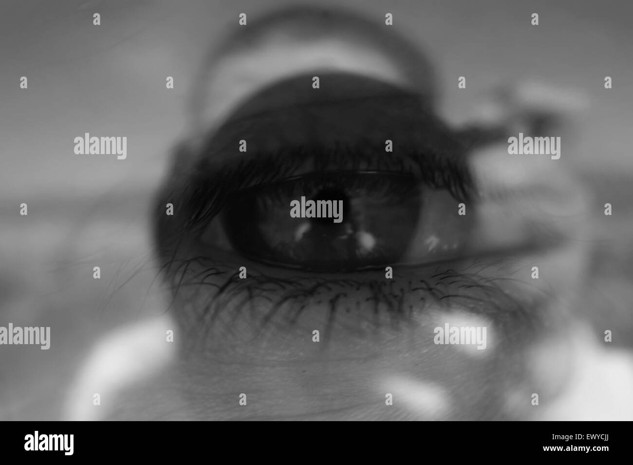 'Photographers eye' conceptual image.BW version.Eye reflected on glass surface showing photographer pressing the shutter button. Stock Photo