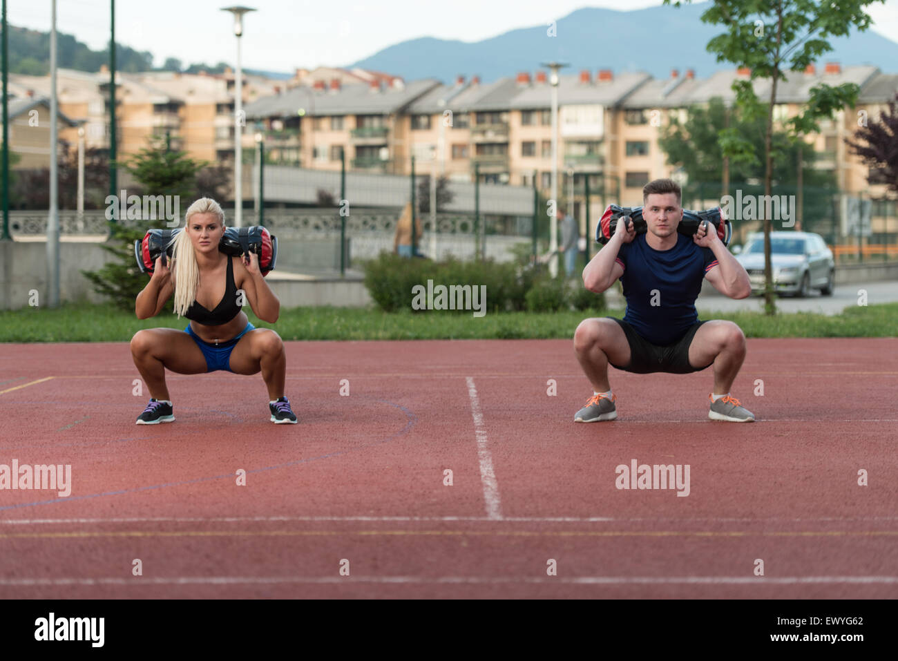 A Group Of Young People In Aerobics Class Performing Bag Squat Exercise