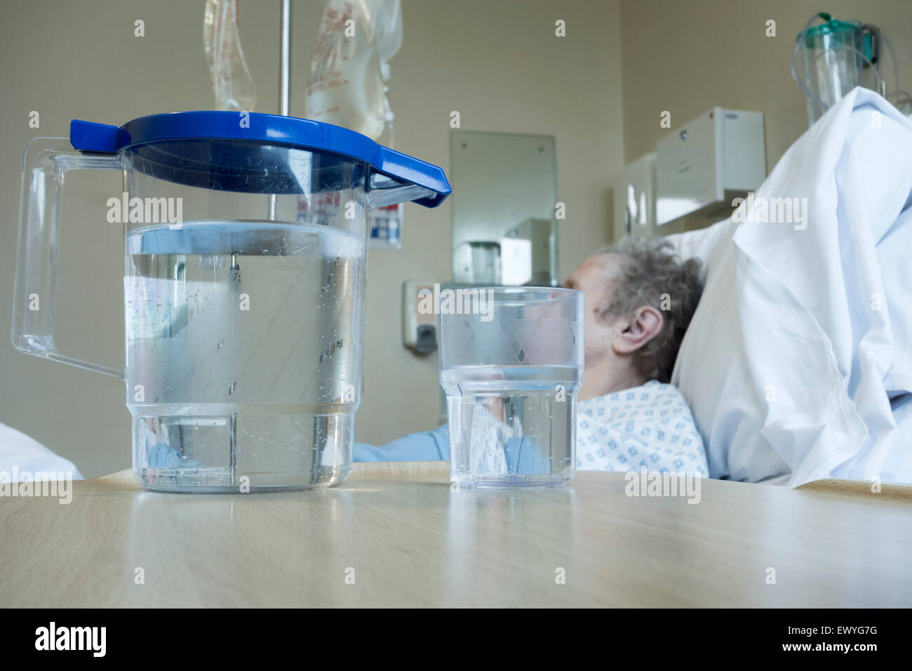 Elderly lady in her nineties in bed on NHS hospital ward with jug of water on bedside table. Stock Photo