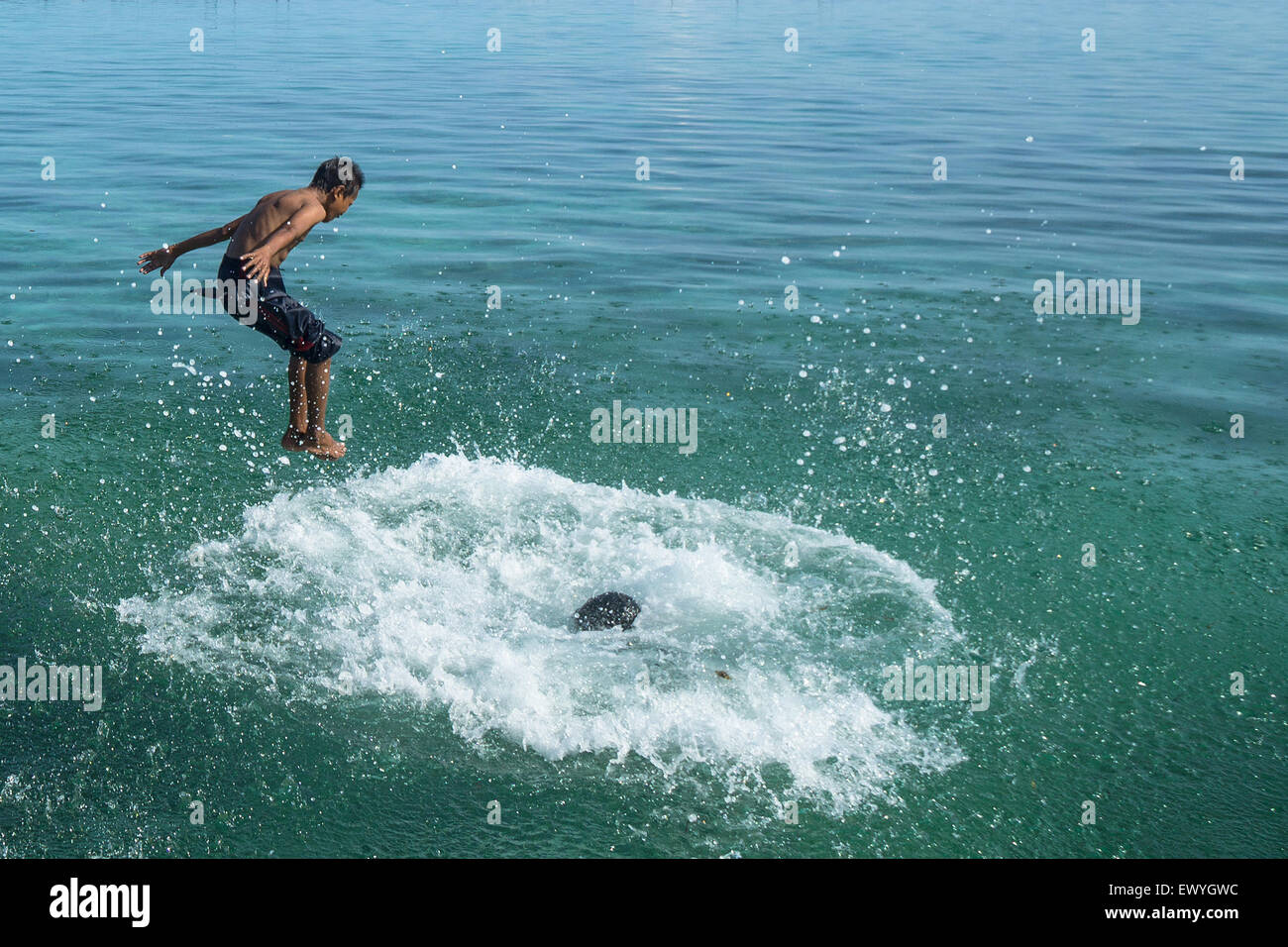 Two boys jumping into the sea, Salakan Island, Semporna, Sabah, Malaysia Stock Photo