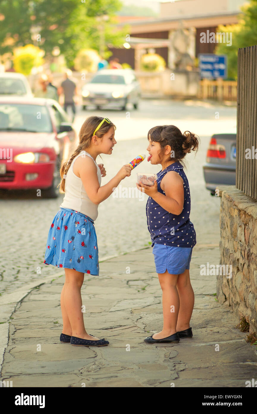 Two girls sharing icecreams in the street Stock Photo Alamy