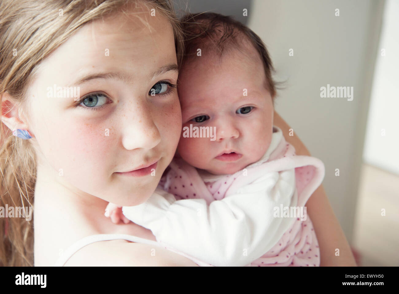 Girl holding her newborn baby sister Stock Photo