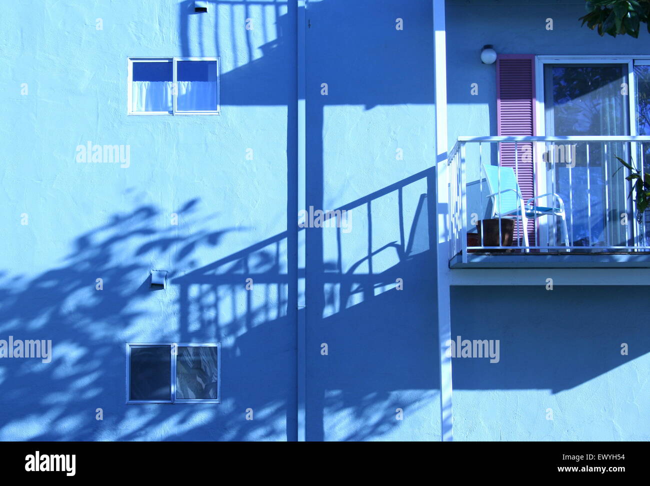 Blue coastal apartment with balcony, shadows cast by sunset, California. Stock Photo