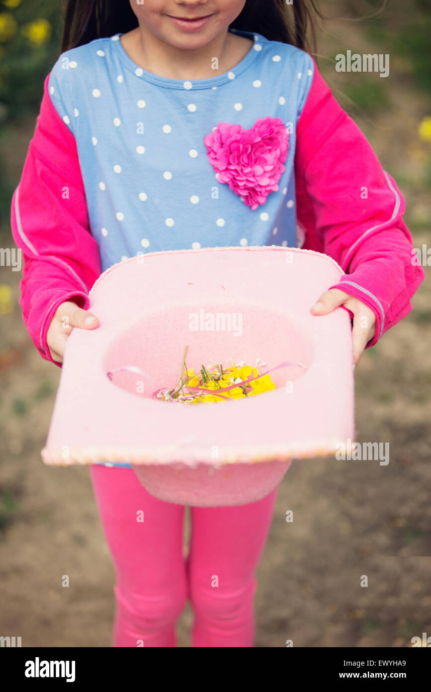 Girl holding a hat filled with flowers Stock Photo