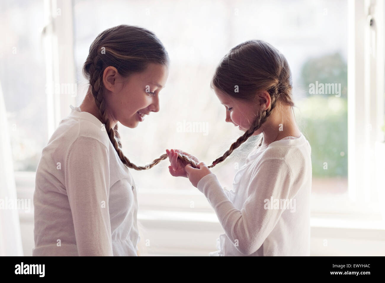 Two girls with their plaits tied together Stock Photo