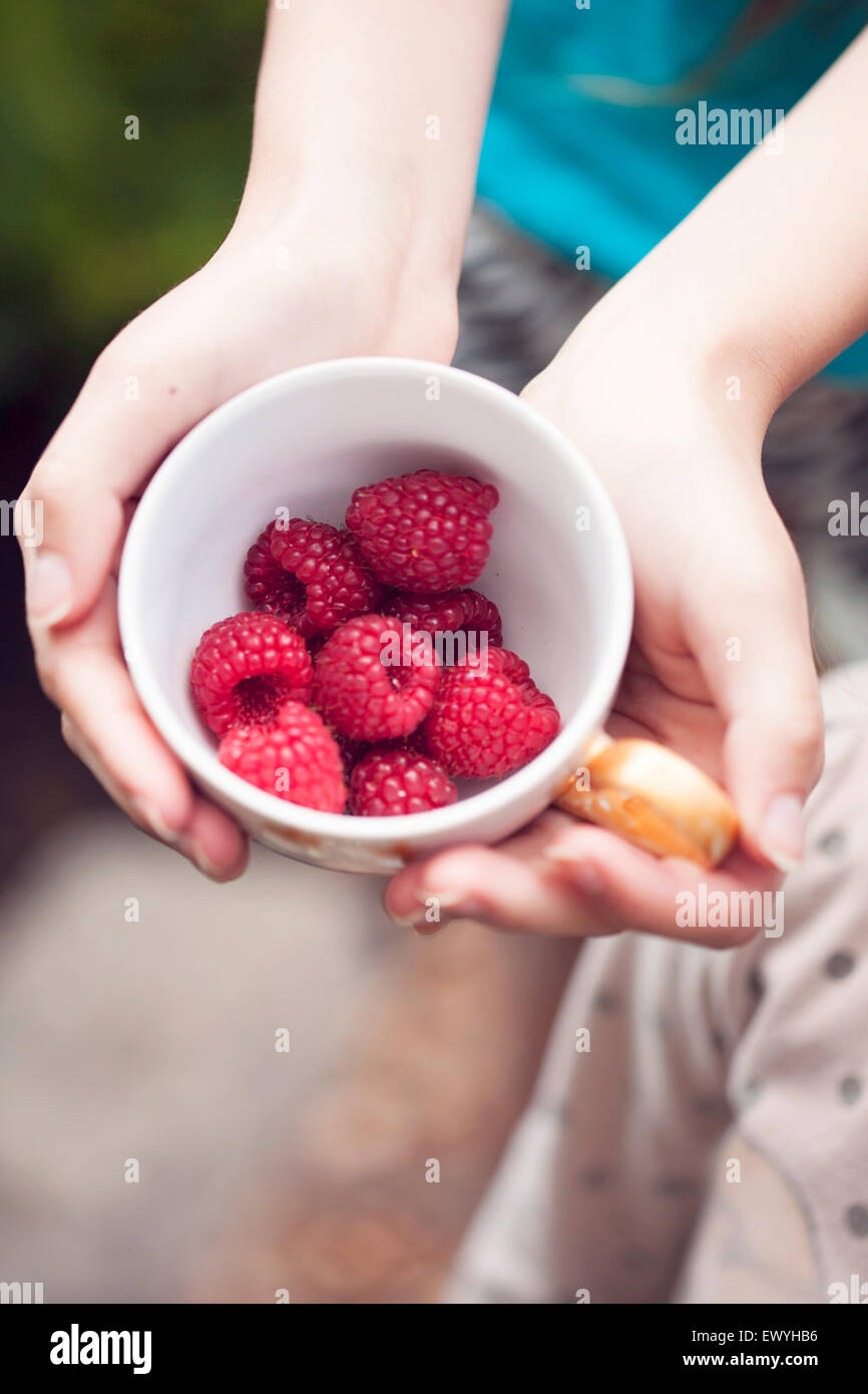 Girl holding Cup with Raspberries Stock Photo