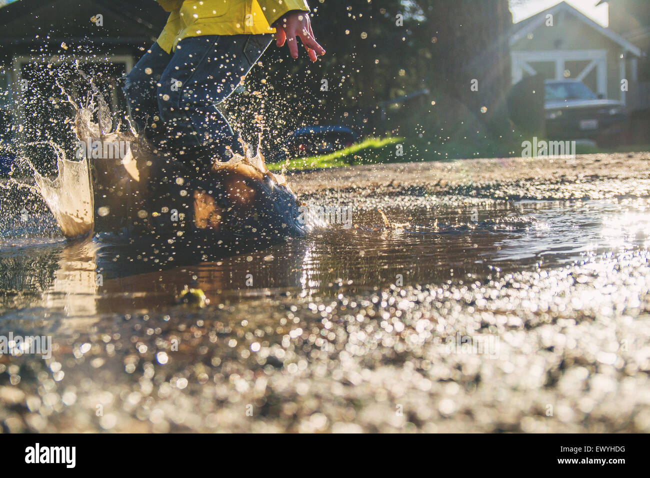 Boy jumping in puddle of muddy water Stock Photo