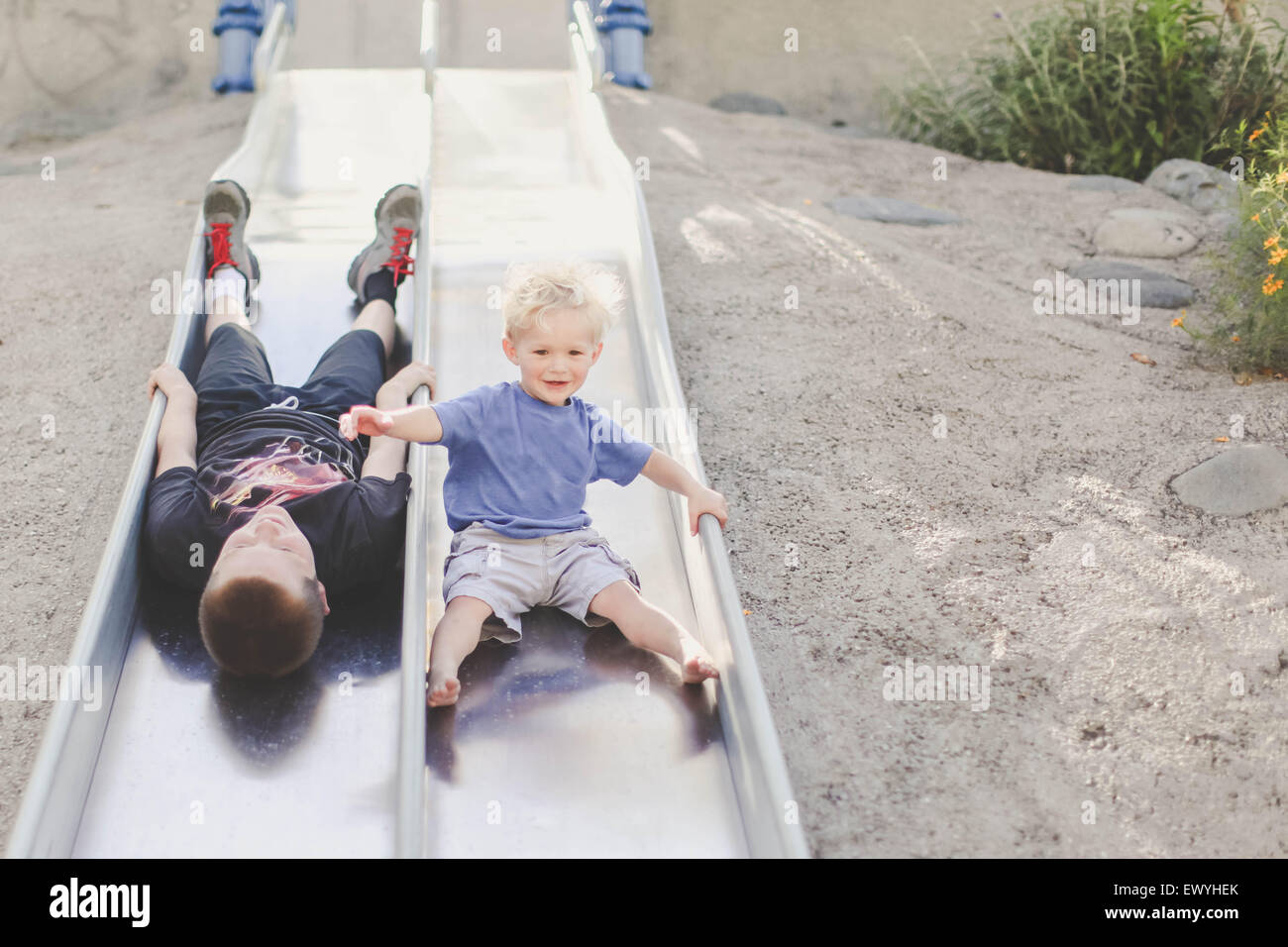 Two boys playing on  a slide at playground Stock Photo