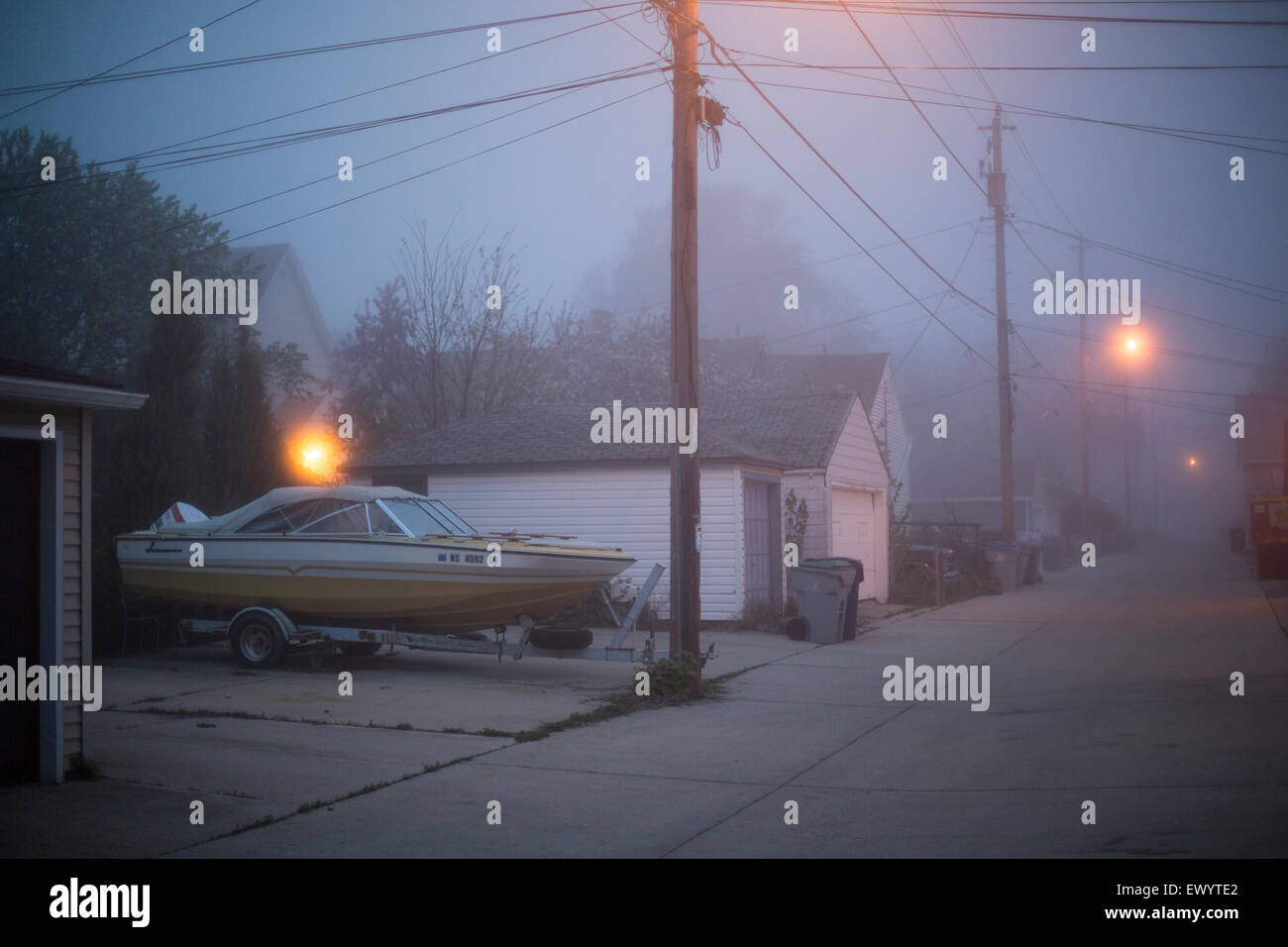 A foggy urban landscape at dusk with a boat parked in an alley Stock Photo