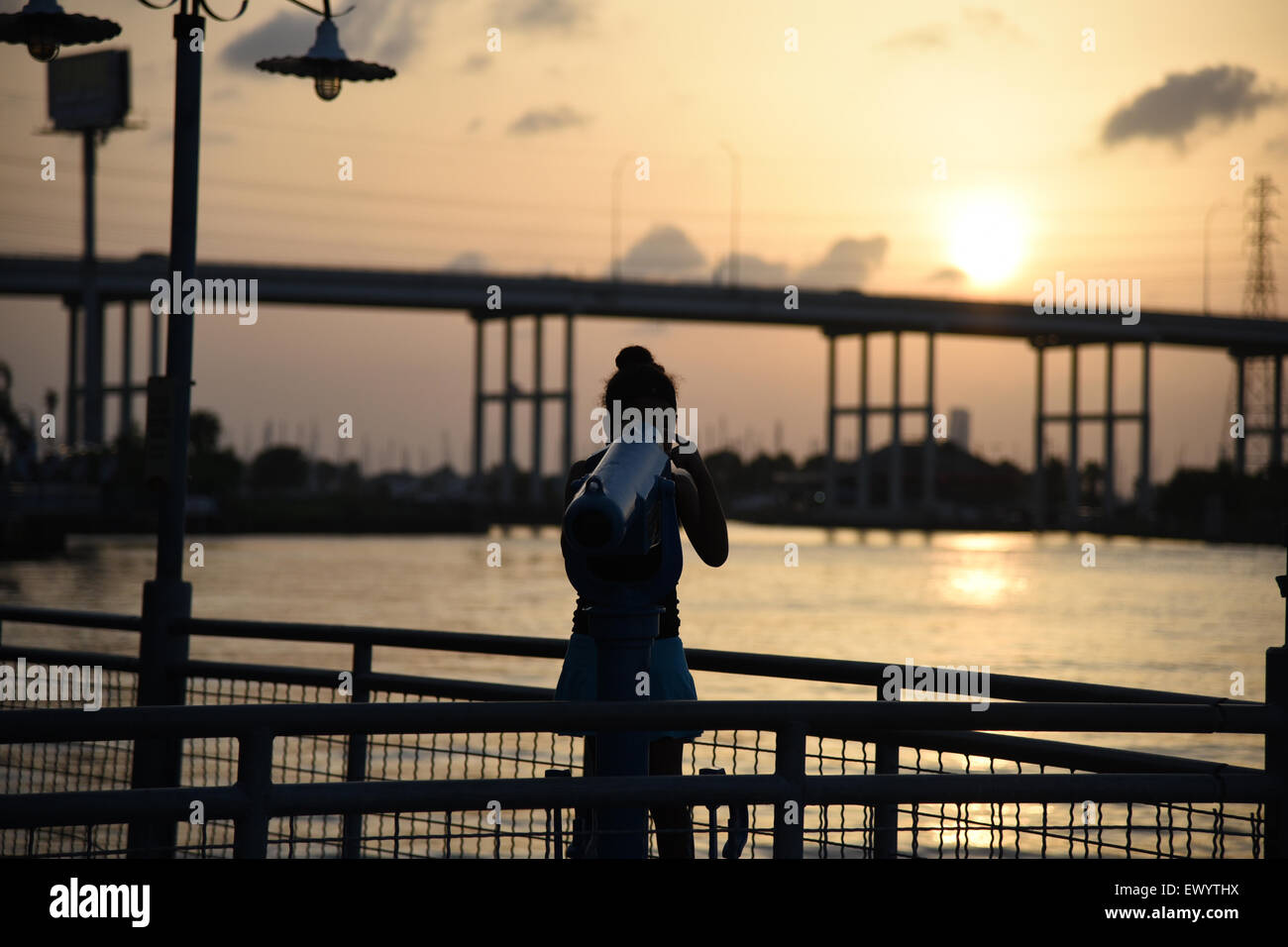 Girl looking through telescope at sunset Stock Photo