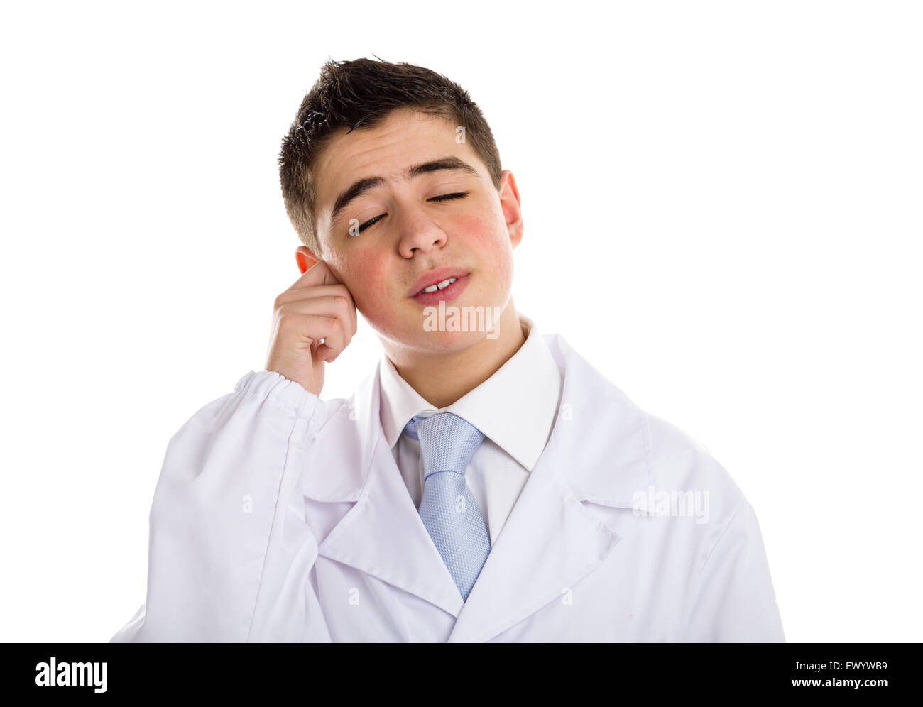 A boy doctor in white coat and blue tie helps to feel medicine more friendly: he is touching his ear with fingers. His acne skin has not ben retouched Stock Photo