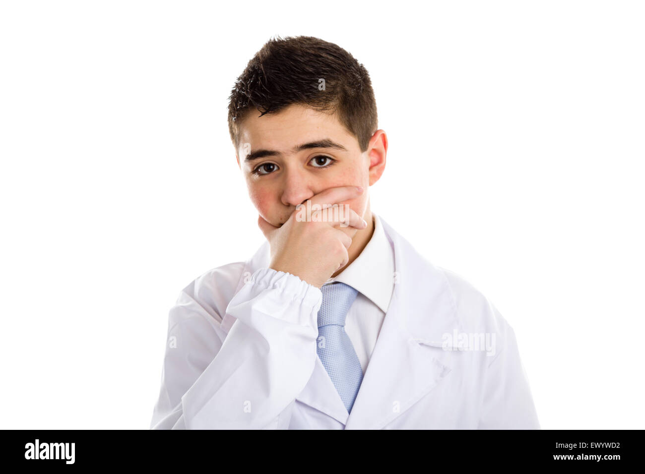 A boy doctor in blue tie and white coat touch his nose covering his mouth with hand: usually this gesture means thinking and expressing doubts about a speech. His acne skin has not ben retouched Stock Photo