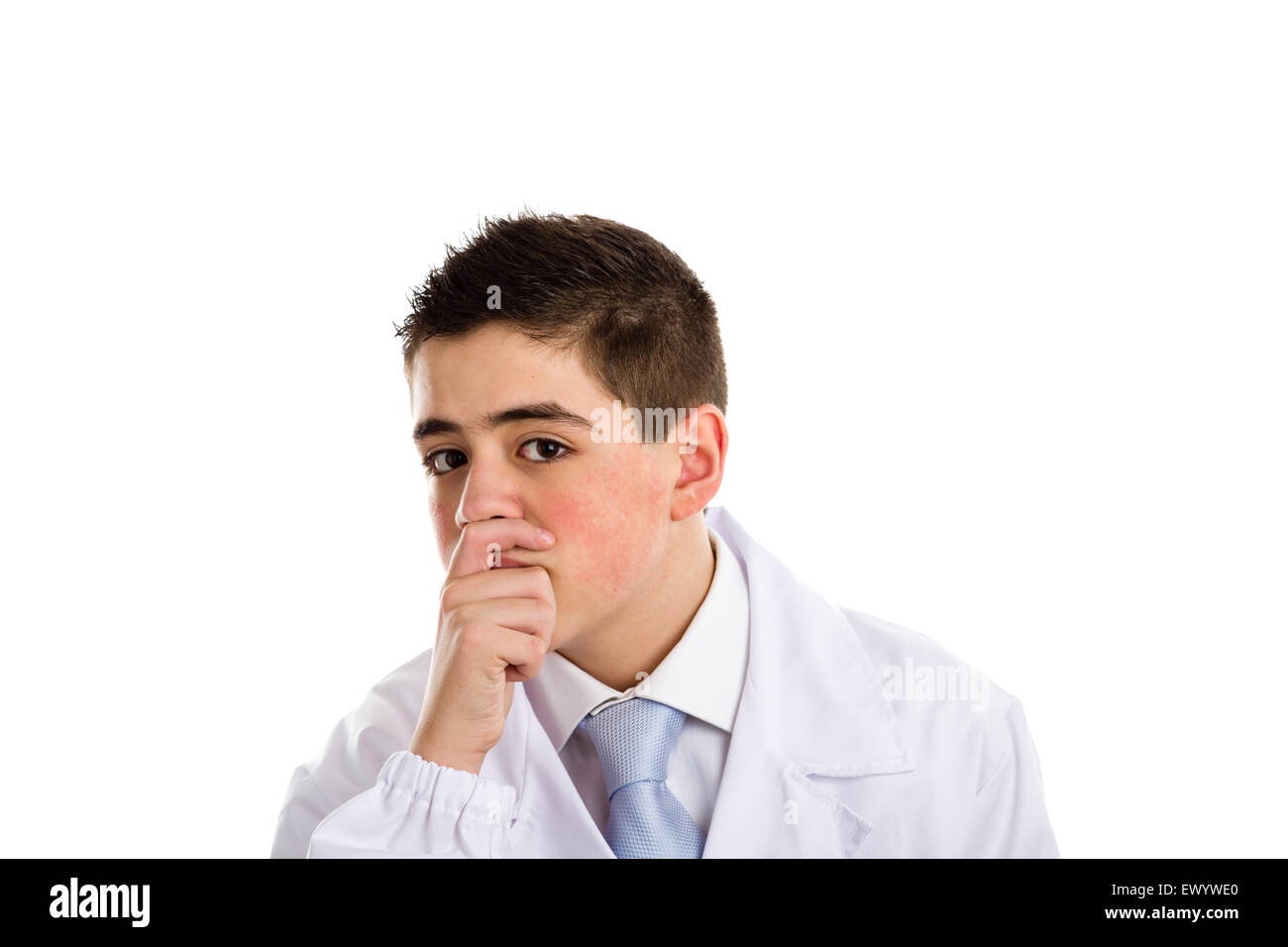 A boy doctor in blue tie and white coat touches his nose covering his mouth with hand: usually this gesture means thinking and expressing doubts about a speech. His acne skin has not ben retouched Stock Photo