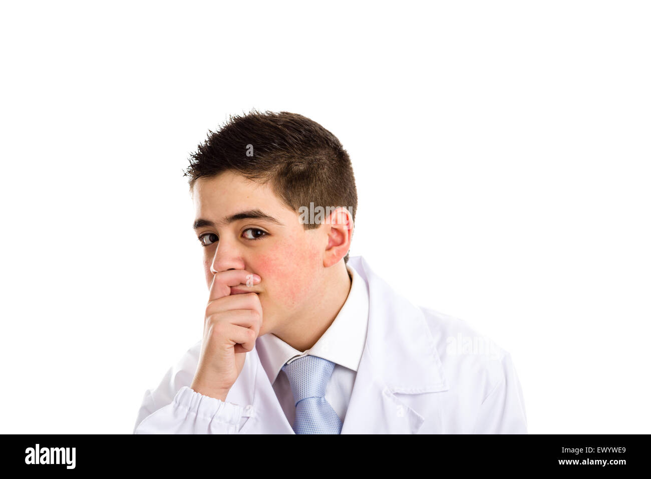 A boy doctor in blue tie and white coat touches his nose covering his mouth with hand: usually this gesture means thinking and expressing doubts about a speech. His acne skin has not ben retouched Stock Photo