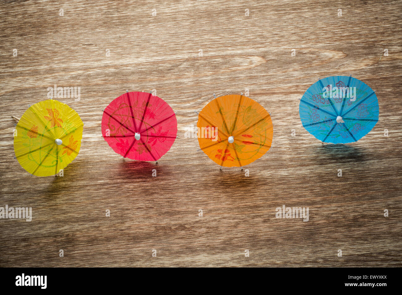 Colourful cocktail umbrellas lying on a wooden backdround, conceptual for partying and festivity Stock Photo