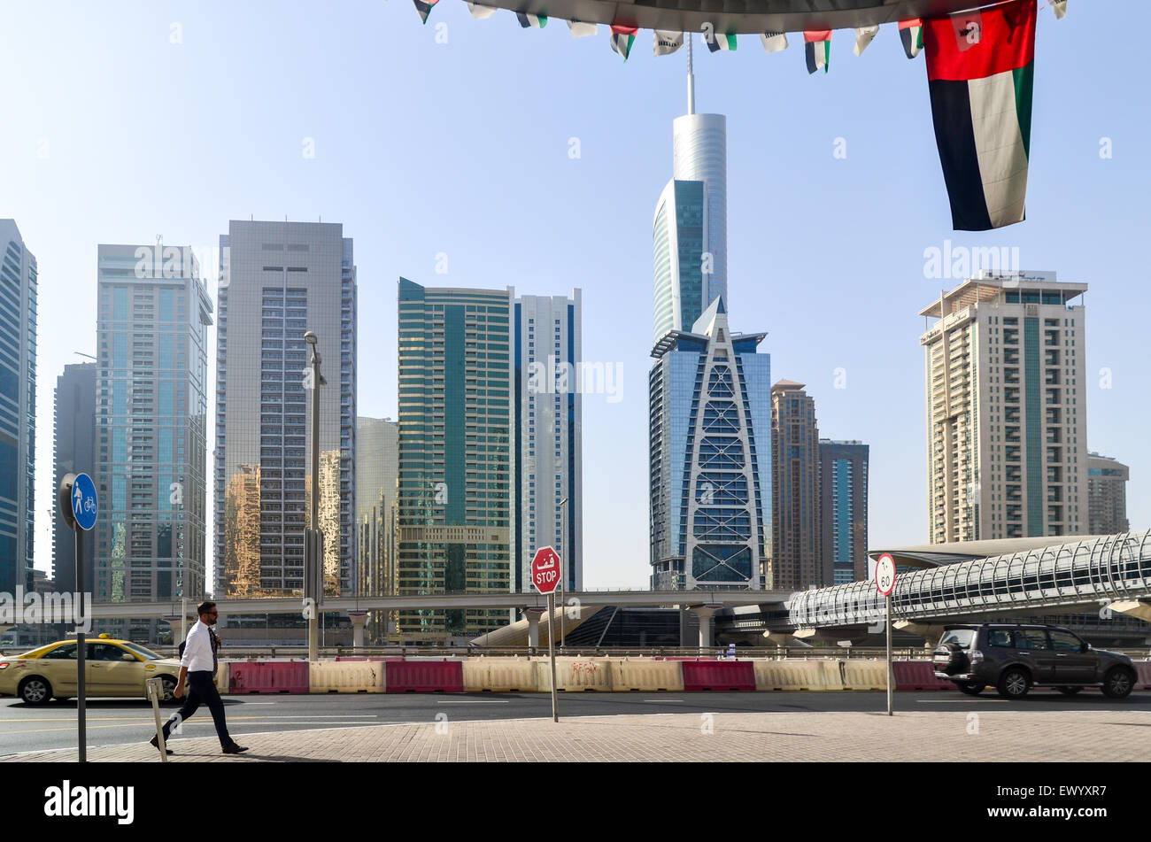 Businessman in Dubai walking under the UAE flag in front of the Jumeirah Lake Towers Stock Photo