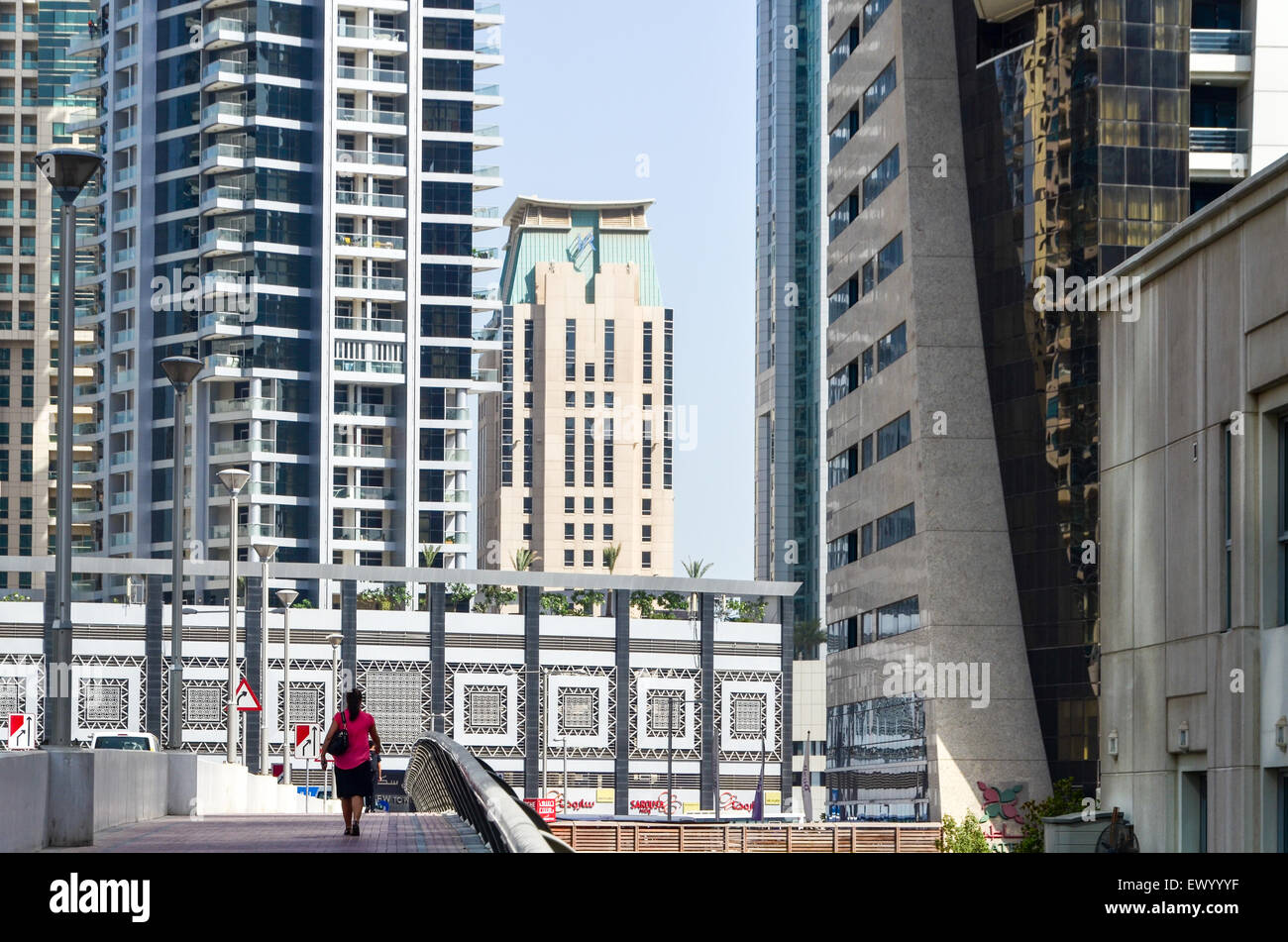 Woman walking between the modern high rise buildings, towers and hotels of the Dubai Marina, United Arab Emirates Stock Photo