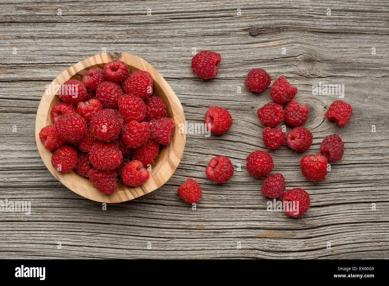 Raspberries in olive wood bowl on old wooden background Stock Photo