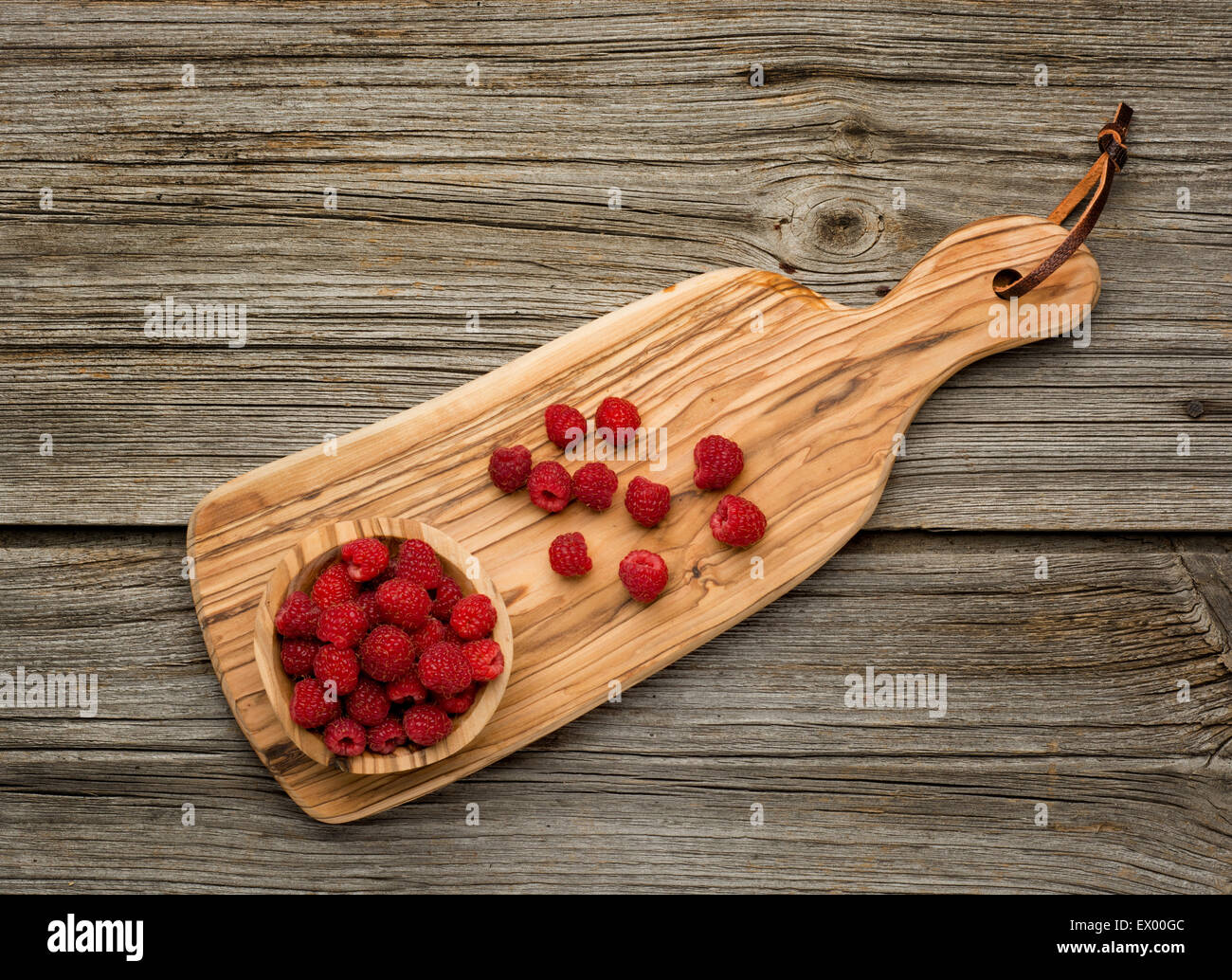 Raspberries in olive wood bowl on old wooden background Stock Photo