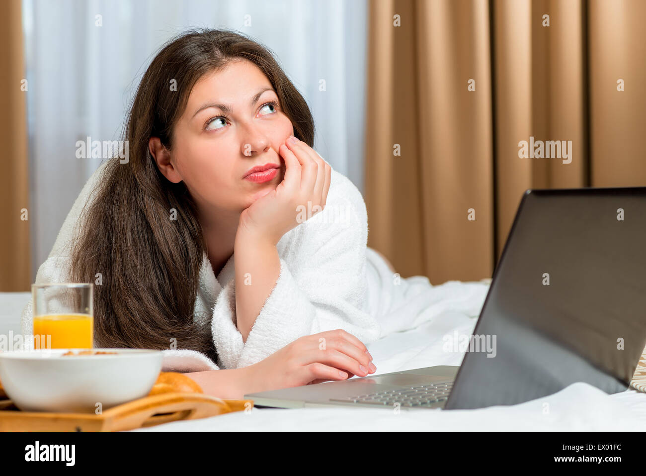 thoughtful girl working lying down on bed in the morning Stock Photo