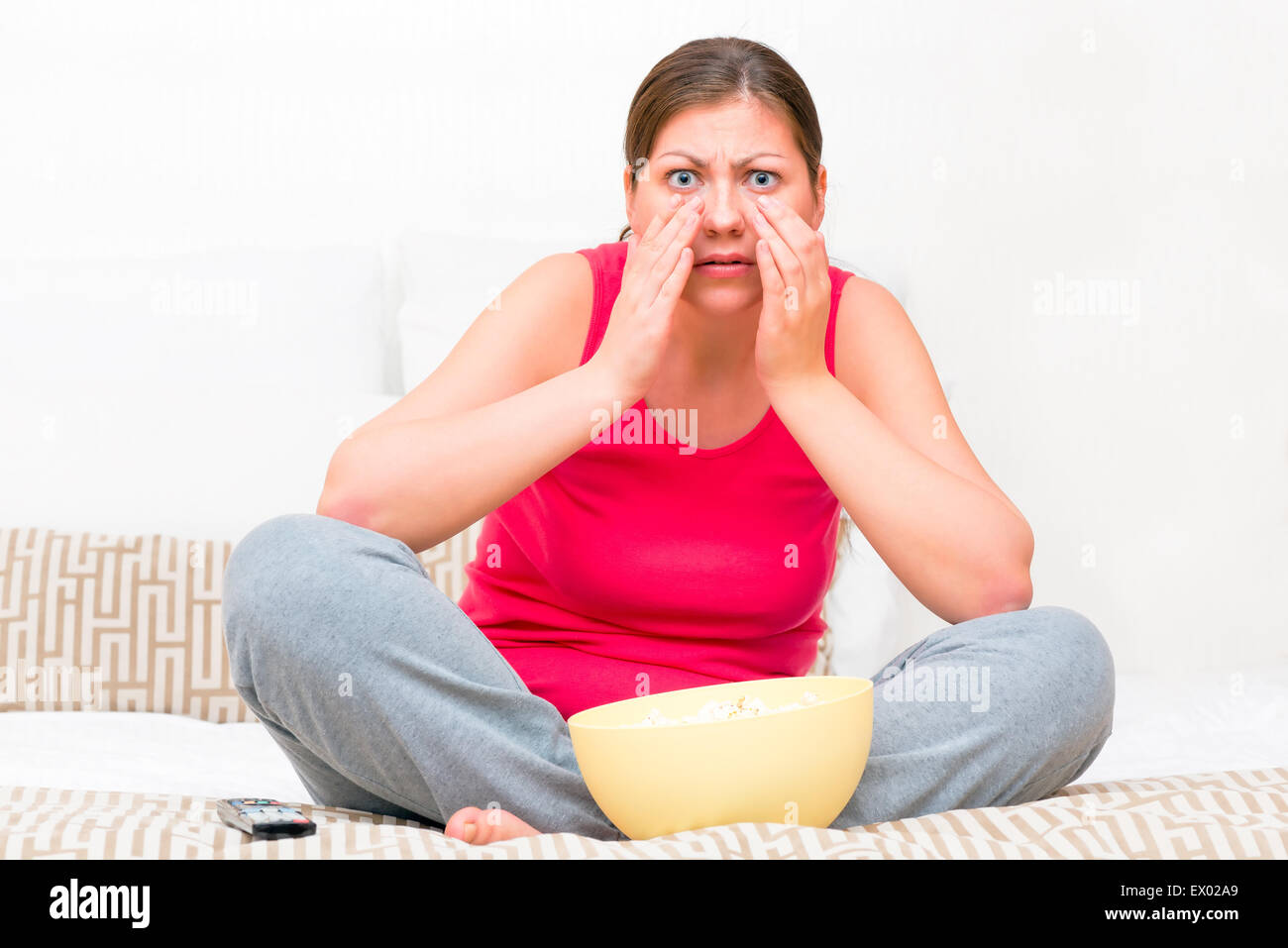 emotional woman watching a horror movie on TV Stock Photo