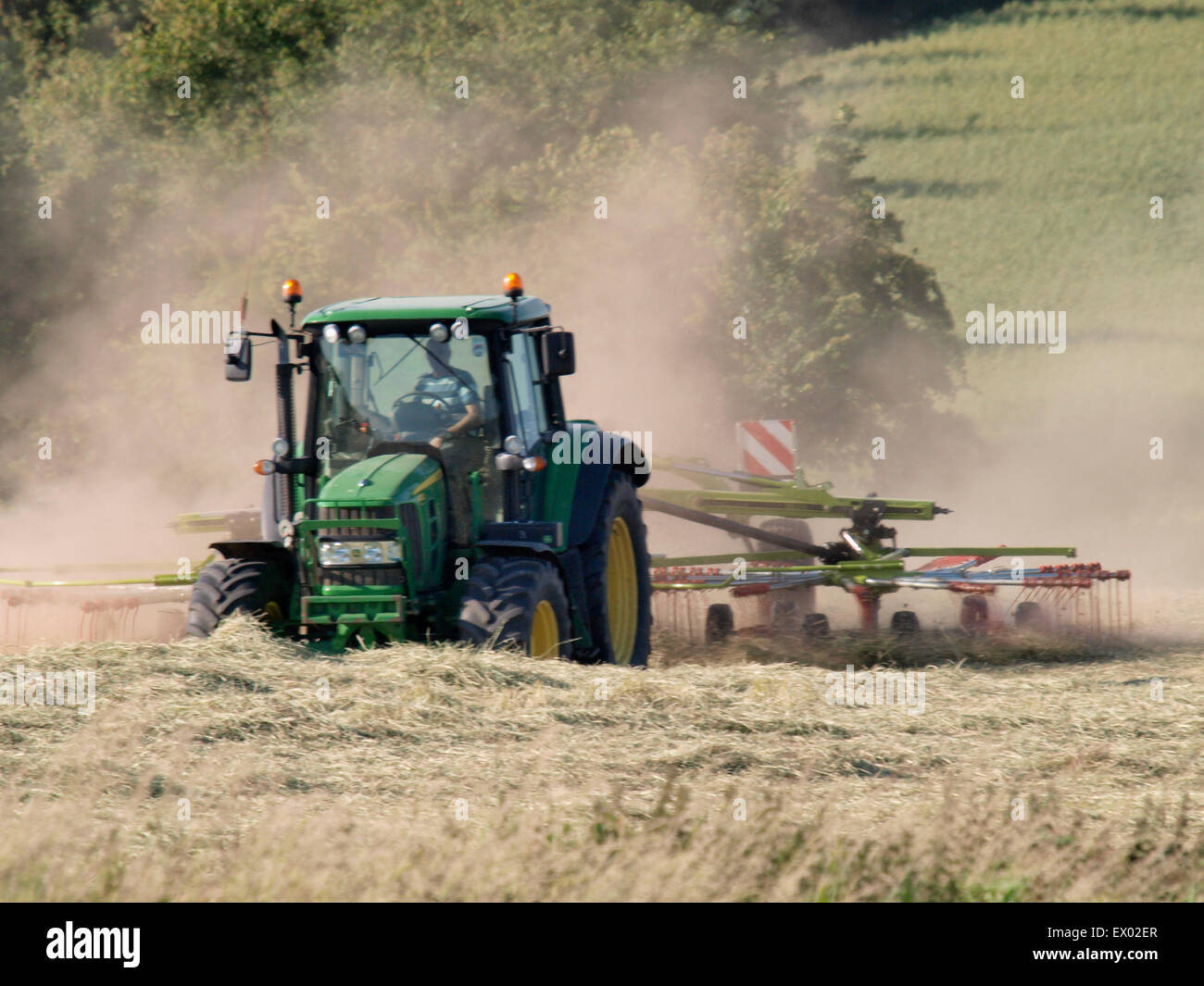 Farmer making lots of dust using a rotary Rake, Somerset, UK Stock ...