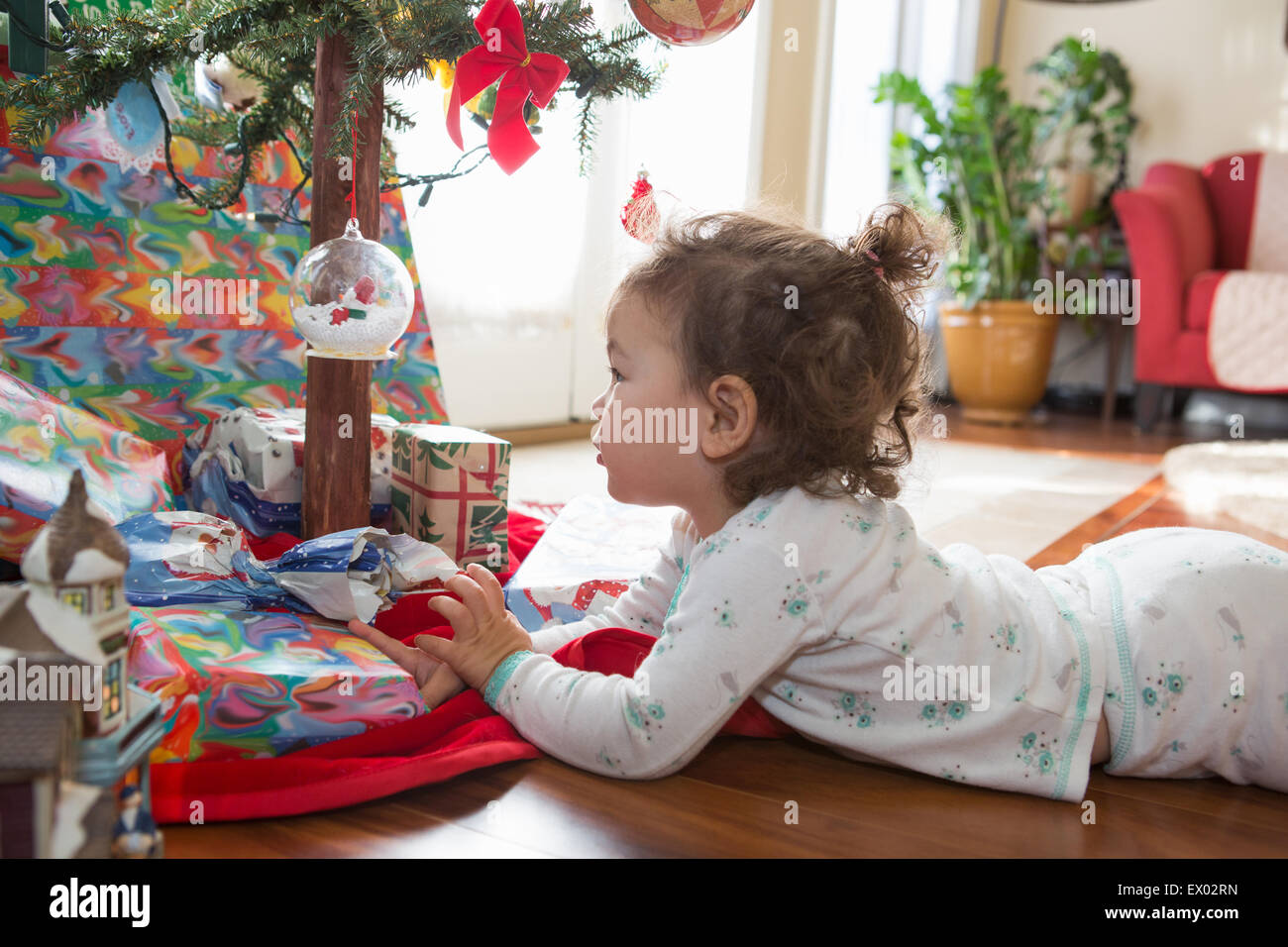 Little girl admiring Christmas ornaments on tree Stock Photo