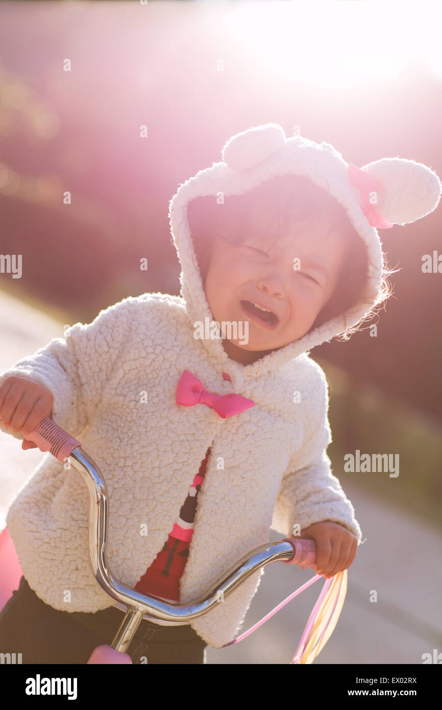 Little girl learning to ride tricycle Stock Photo