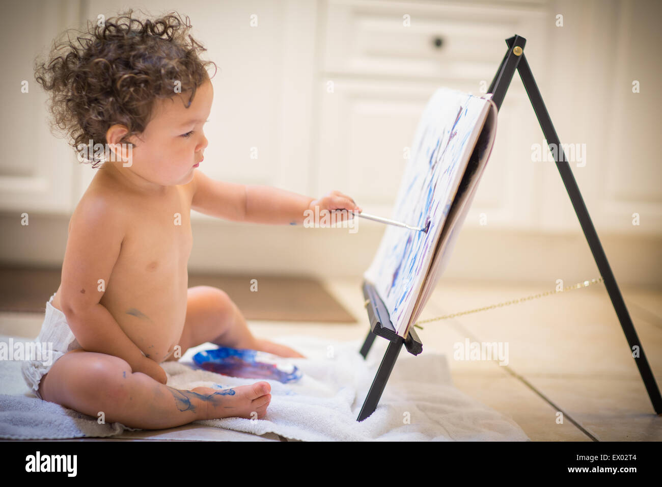 Little girl painting in kitchen Stock Photo