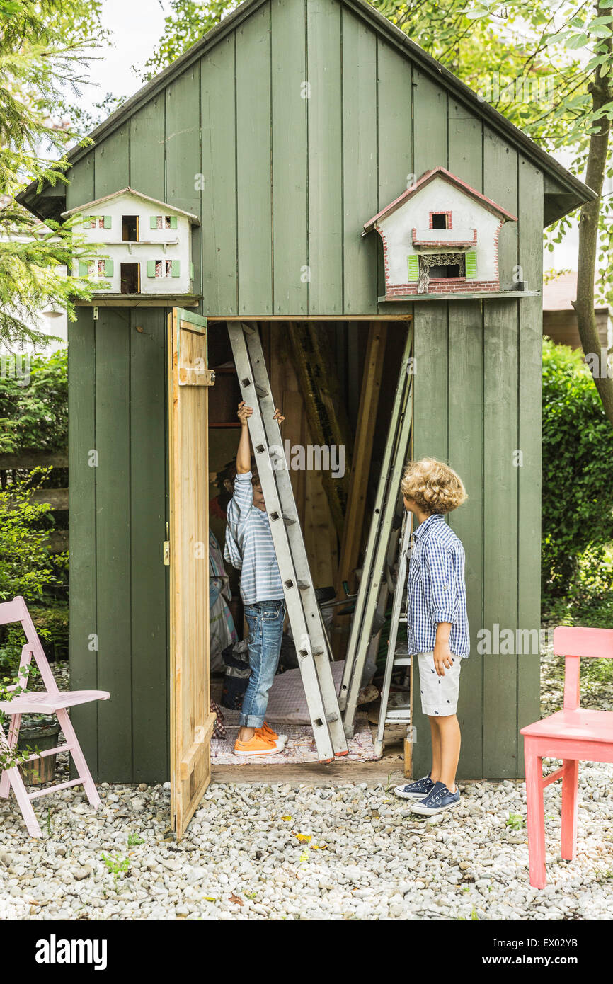 Two brothers removing ladder from garden shed Stock Photo