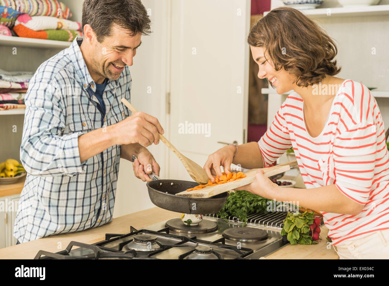 Couple preparing to cook fresh vegetables in kitchen Stock Photo