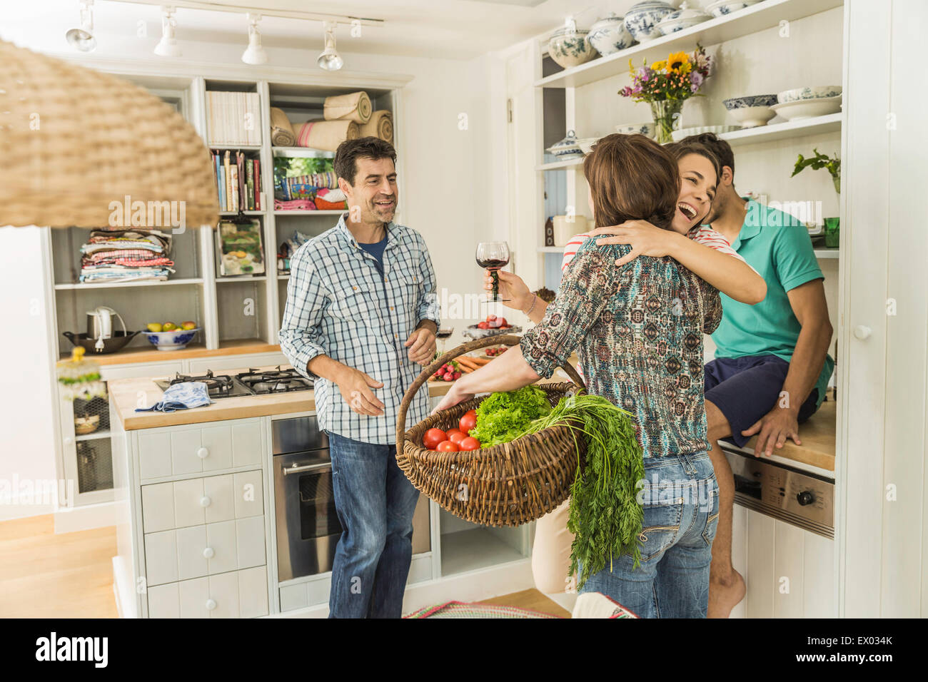 Four adult friends greeting in kitchen Stock Photo