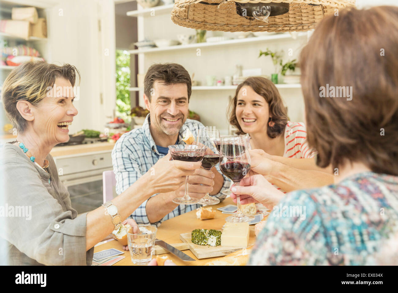 Adult friends making a toast with red wine at dining table Stock Photo