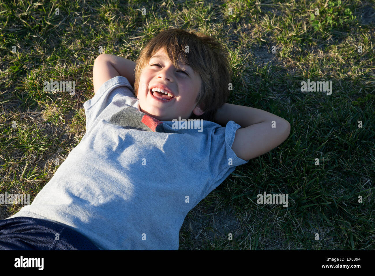 Portrait of boy lying on park grass and laughing Stock Photo