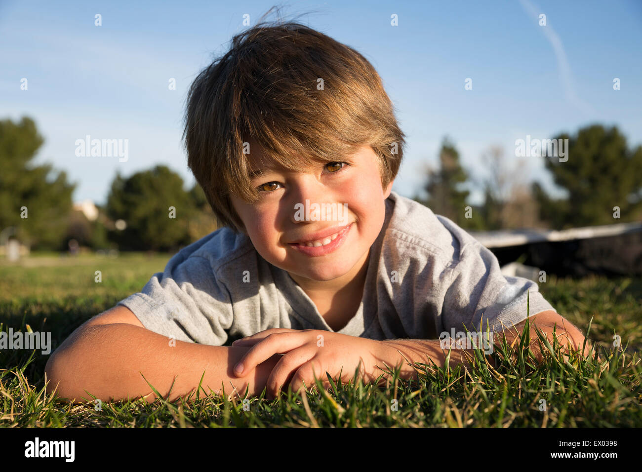 Portrait of smiling boy lying on park grass Stock Photo