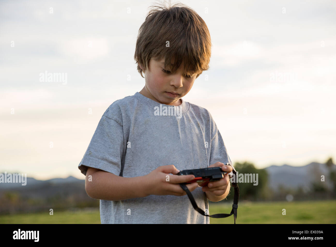 Boy looking at digital camera in park Stock Photo - Alamy