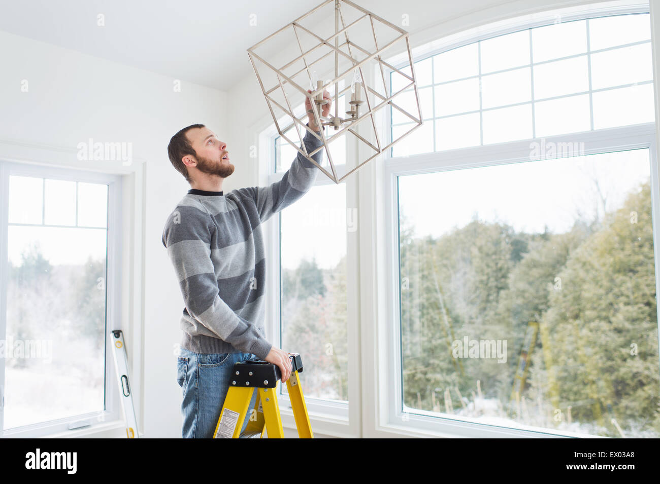 Young man installing ceiling light Stock Photo