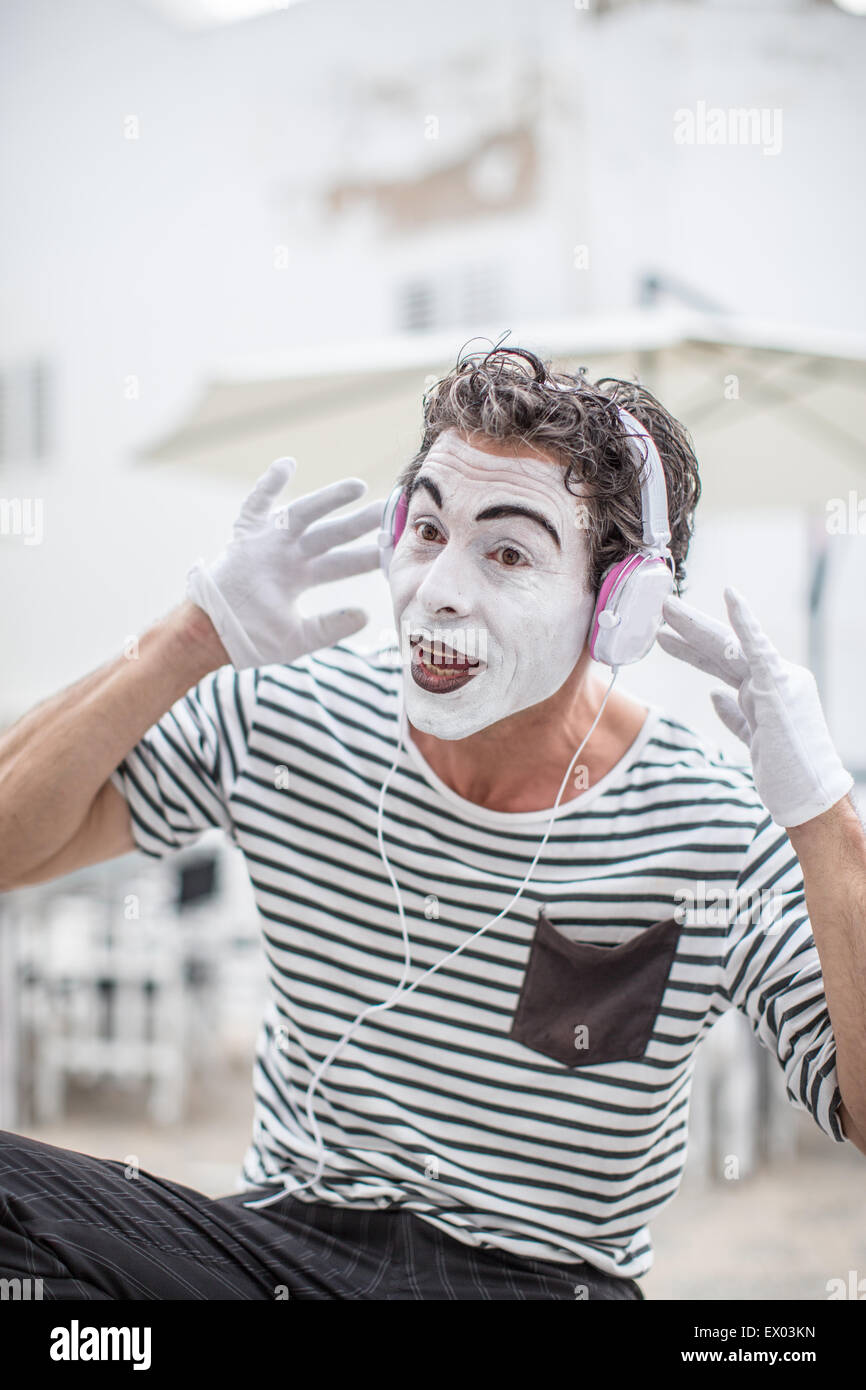 Male mime artist listening to headphones, Ibiza, Spain Stock Photo