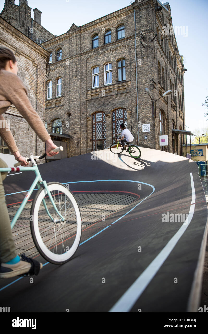 Male and female cyclists racing uphill on city velodrome, Riga, Latvia Stock Photo
