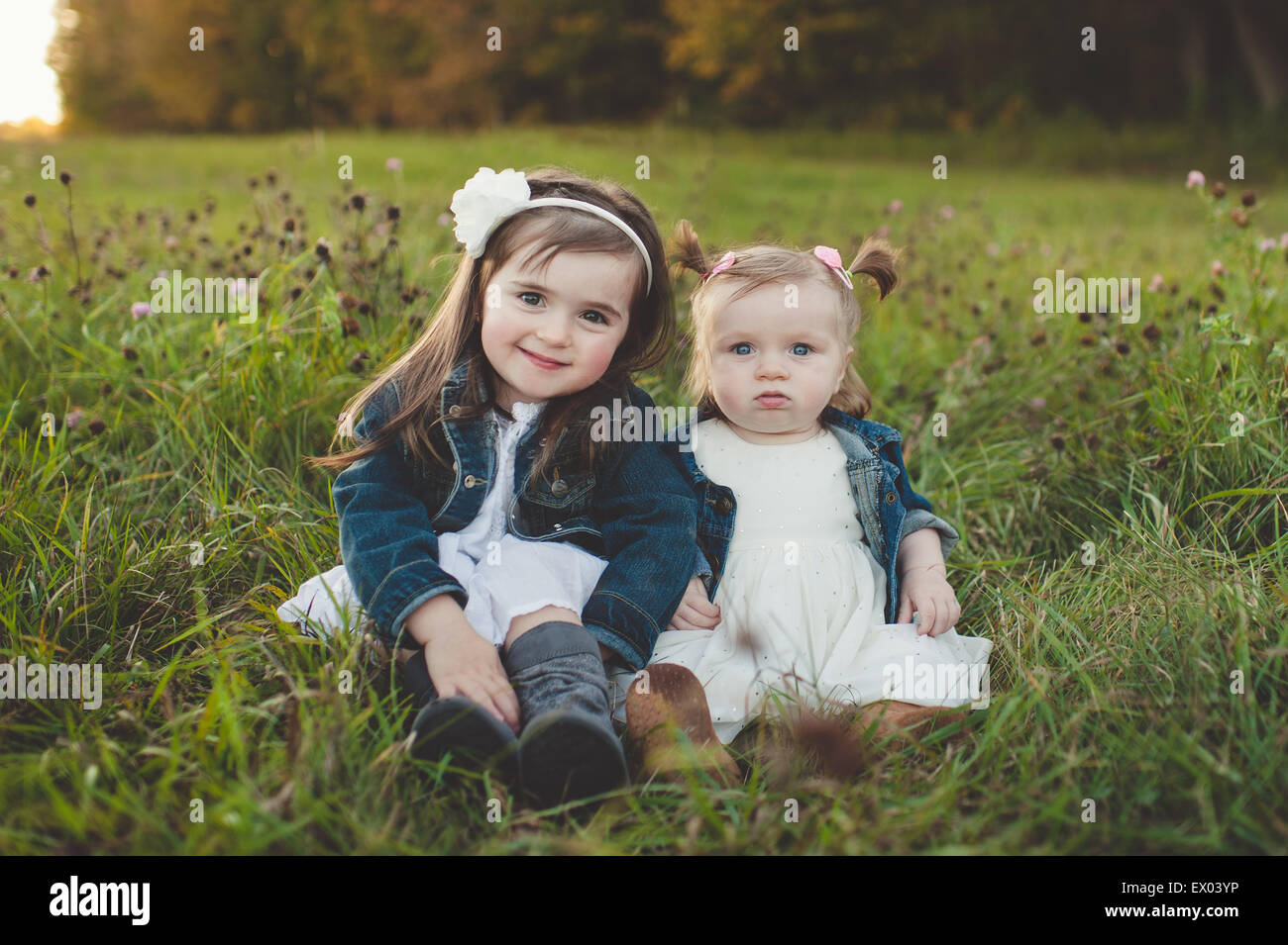 Portrait of young girl and baby sister in field Stock Photo