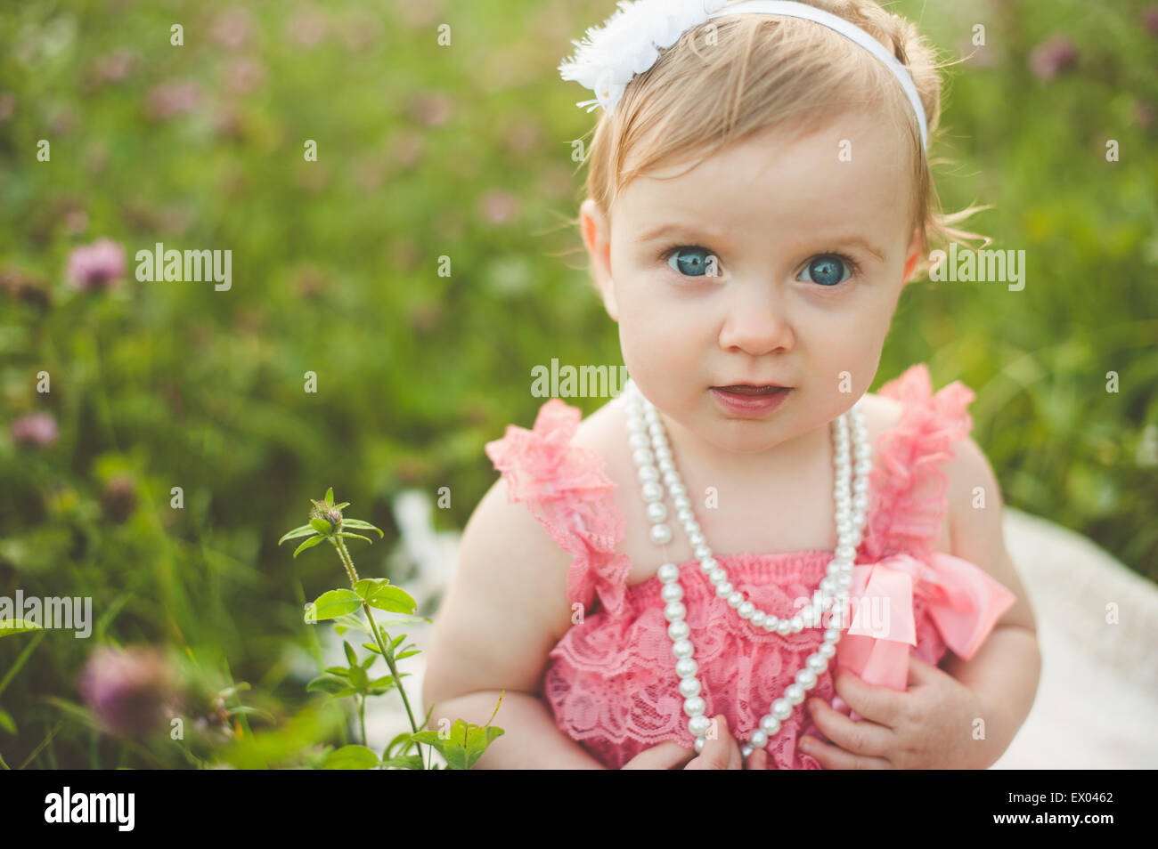 Portrait of blue eyed baby girl in meadow Stock Photo