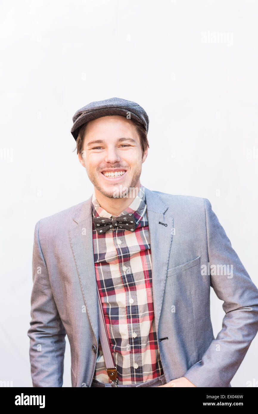 Portrait of young man wearing silver suit jacket and flat cap Stock Photo